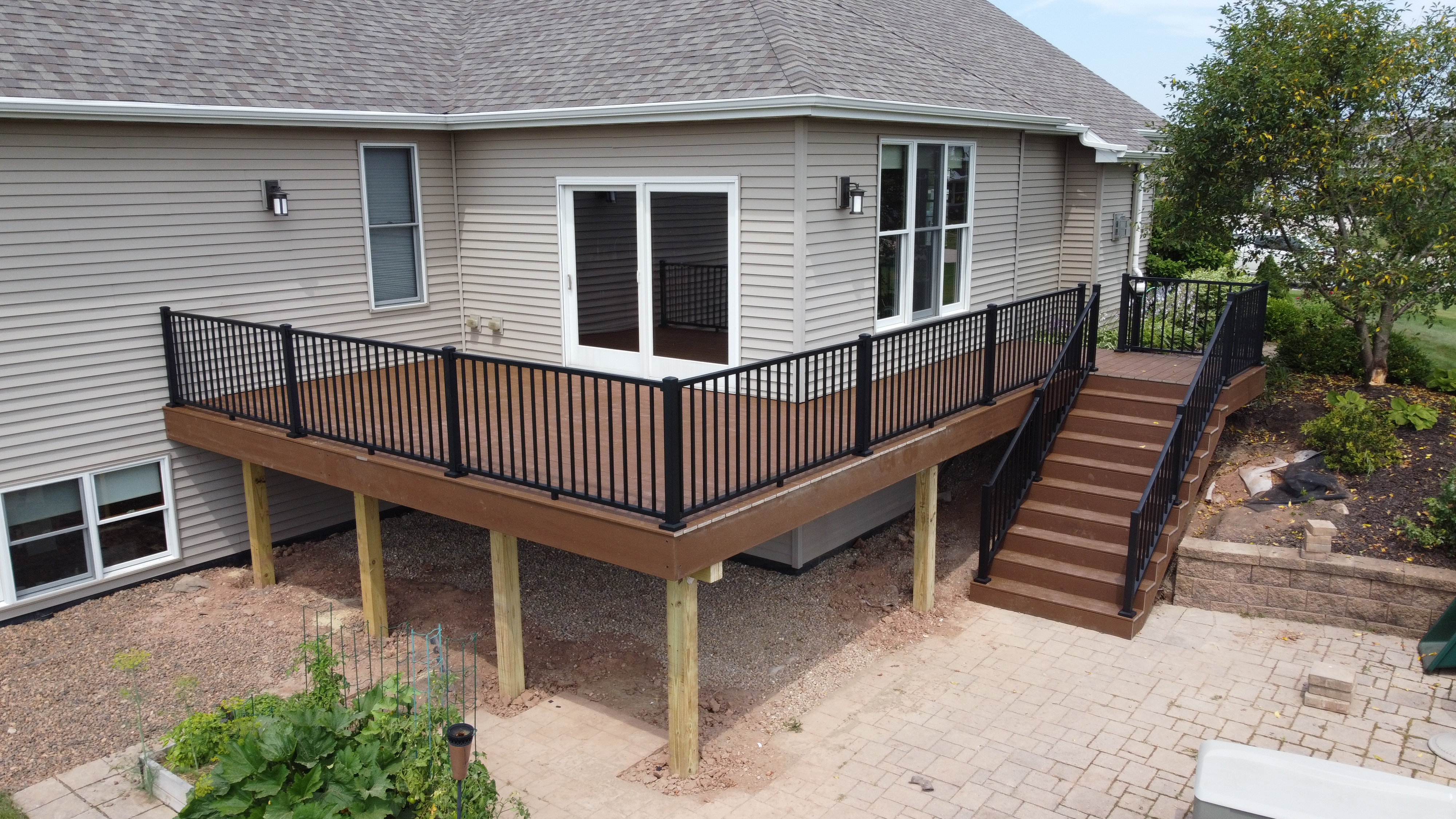 Deck builder Appleton. Elevated Trex composite deck attached to a tan house built by the deck builder Nothin' but Decks in Greenville WI