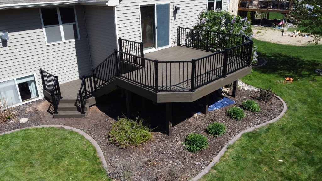 Elevated Trex Enhance Naturals Coastal Bluff composite deck attached to a light tan house